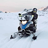 Person Driving Snowmobile in Mountains