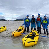 Group of People Standing with Rafts in Shallow Water