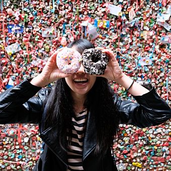 Girl Holding Donuts for Eyes in Front of Gum Wall