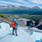 Man Standing On Glacier Looking at Mountains