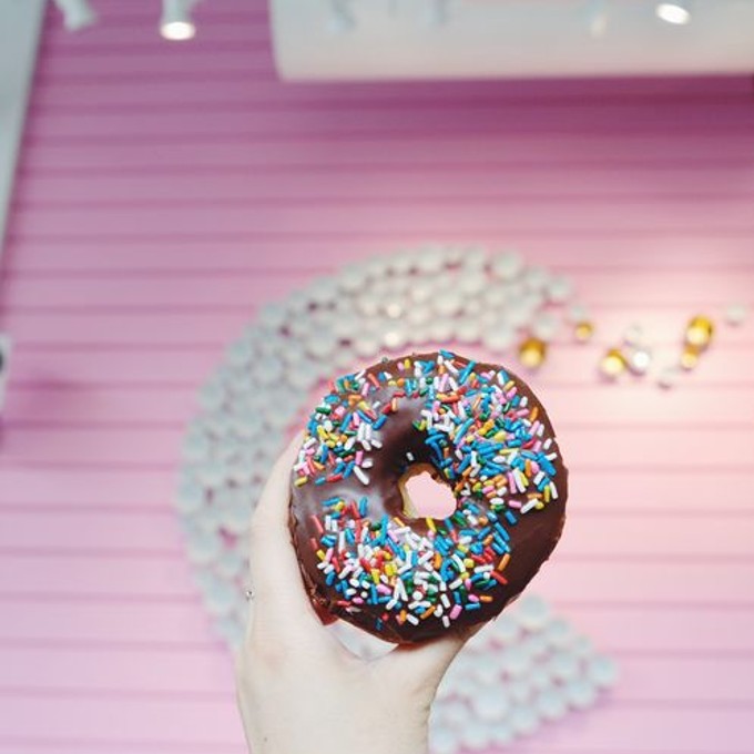 Chocolate Donut with Rainbow Sprinkles on Pink Background
